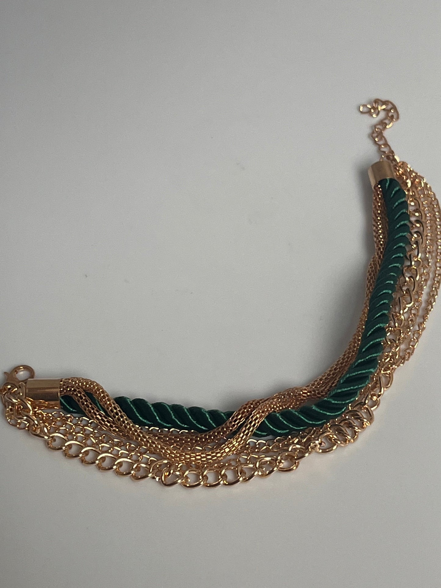 Gullfarget armbånd med grønn tråd.